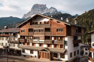 a large wooden building with a mountain in the background at Best Western Hotel Nevada in San Vito di Cadore