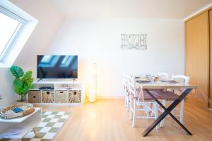a dining room with a table and a tv at Le Cocon I Hyper Centre & Calme in Crozon