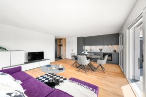 a living room with a purple couch and a table at Penthouse Exclusif - Grande Terrasse - Avenches - Self Check-in in Avenches