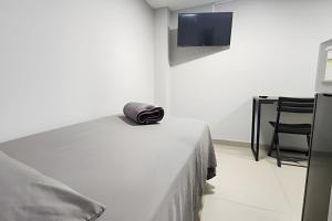 a bedroom with a bed and a chair and a flat screen tv at Studio VI - Com Ar Condicionado in Jundiaí