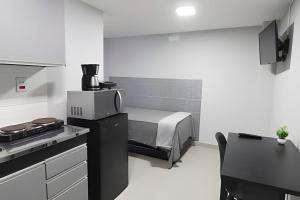 a small kitchen with a bed in the background at Studio VI - Com Ar Condicionado in Jundiaí +5 photos