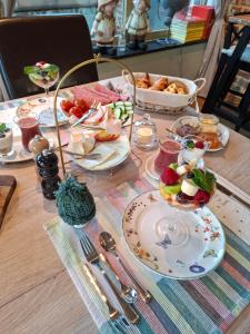 a table with plates of food and a bowl of fruit at B&B Kerkevelde in Bilzen