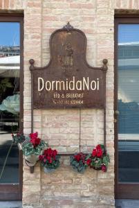 a sign on the side of a building with flowers at DormidaNoi B&B in Civitanova Marche