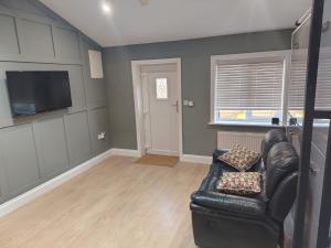 a living room with a leather couch and a television at Tramway Apartment in Blessington