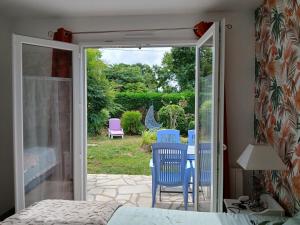 a bedroom with a door open to a patio with chairs at Le triskel bleu in Saint-Thual +10 photos