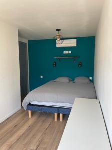 a bedroom with a bed with a blue wall at Loft industriel avec jacuzzi in Le Bourgeat