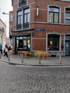 a brick building with yellow tables and chairs on a street at Urban Maghin in Liège