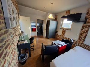 a room with a bed and a desk and chairs at B&B Kerkevelde in Bilzen