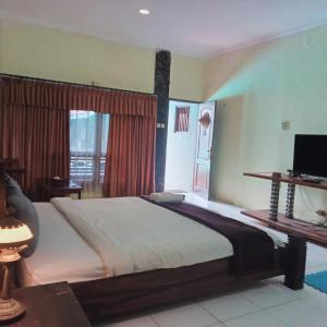 a bedroom with a large bed and a television at Palagan Boutique Hotel in Ngaglik +4 photos