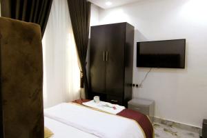 a hotel room with a bed and a flat screen tv at Dawn Emeka Hotels in Akwa