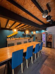 a dining room with a large wooden table and blue chairs at Loft industriel avec jacuzzi in Le Bourgeat