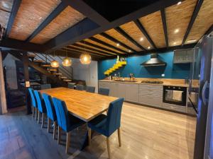a kitchen with a wooden table and blue chairs at Loft industriel avec jacuzzi in Le Bourgeat