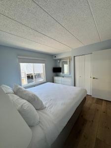 a large white bed in a room with a window at Wild Dunes Inn in Ocean City +6 photos