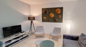 a living room with a couch and a tv and chairs at HISTOIRE DE LOIRE - La Maison in Saumur