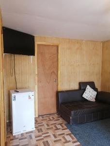 a living room with a black leather couch and a door at Cabañas Montina Hualqui piscina y tinaja in Concepción