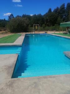 a large blue swimming pool with a playground at Cabañas Montina Hualqui piscina y tinaja in Concepción