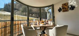 a table and chairs in a room with a large window at Les Chalets d'Offaz - Centre Abondance - Alp'in C in Abondance +16 photos