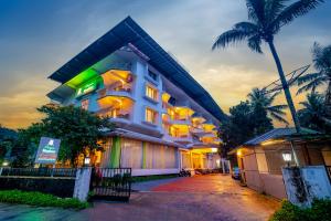 a building with a palm tree in front of it at Periyar Meadows Leisure Hotel in Thekkady