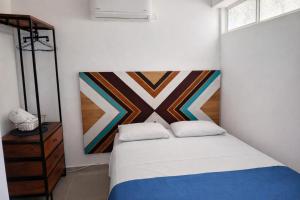 a bedroom with a bed and a painting on the wall at Hostal Nomadas in Santa Marta +28 photos
