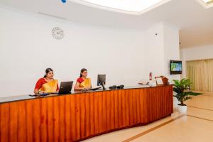 two women are standing at a reception desk at Periyar Meadows Leisure Hotel in Thekkady