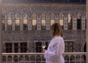 a woman holding a glass of wine in front of a building at Boutique-Hôtel Le N3 par Champagne Thiénot in Reims