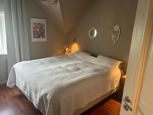 a bedroom with a white bed with a clock on the wall at High rated private appartment 350 m from Ålesund center with free parking in Ålesund