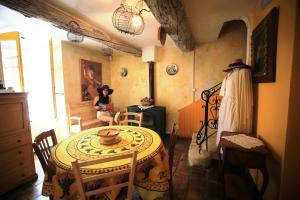 a room with a table and a woman sitting in a room at La Maison du Chichui in Orgon