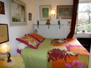 a bedroom with a bed with a colorful blanket at La Maison du Chichui in Orgon