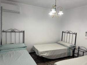 a room with two beds and a chandelier at Cortijo rural Los Pinos in Villanueva de Algaidas +42 photos