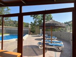 a group of chairs and umbrellas next to a swimming pool at Cortijo rural Los Pinos in Villanueva de Algaidas