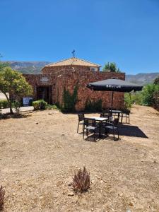 a table and chairs with an umbrella in front of a building at Hotel Rural La Marmita de Ahlam in Fondón