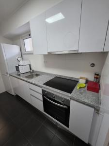 a kitchen with white cabinets and a stove top oven at Art House Madeira II in Caniço