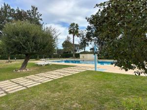 a swimming pool in a park with a tree at Casa das Mélias in Vilamoura