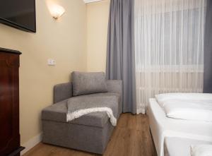 a bedroom with a chair and a bed at Hotel Altmünchen by Blattl in Munich