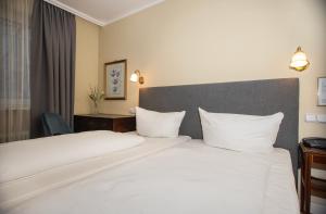 a hotel room with a large bed with white pillows at Hotel Altmünchen by Blattl in Munich