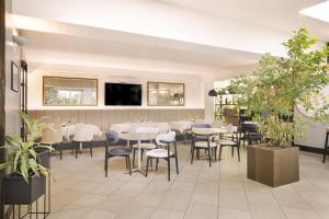 a dining room with tables and chairs and plants at Best Western City Hotel in Bologna