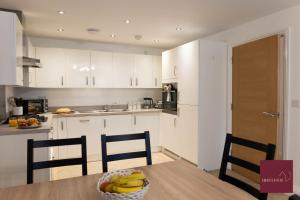 a kitchen with white cabinets and a table with a bowl of bananas at Hook Three Bed Flat Parking in Hook +8 photos