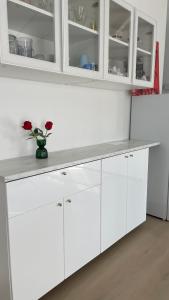 a kitchen with white cabinets and a vase with roses at Dune Nest 233 - beautiful house near beach - up to 4 guests with garden, parking, WLAN in Bredene +12 photos