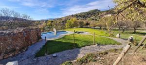 a garden with a swimming pool and a stone wall at Hotel Rural La Marmita de Ahlam in Fondón