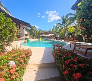 a pool at a resort with benches and flowers at Parti Gras Hotel & Villas en Playa Potrero in Potrero