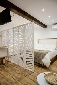 a white bedroom with a bed and a tv at La Maestra Catedral 1 in Jaén