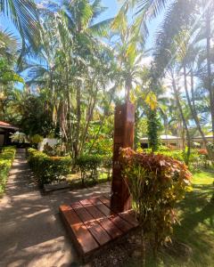 a wooden gate in a garden with palm trees at Parti Gras Hotel & Villas en Playa Potrero in Potrero
