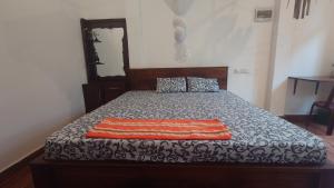 a bed with an orange and white blanket on it at ELEPHANT Orphanage View in Udawalawe +6 photos
