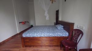 a bedroom with a wooden bed and a red chair at ELEPHANT Orphanage View in Udawalawe