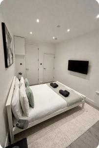 a bedroom with a bed with a tv on the wall at 6 Aviv Place in Addlestone