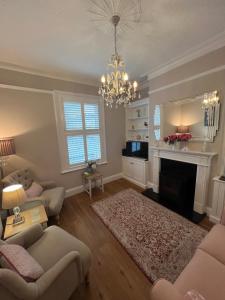 a living room with a chandelier and a fireplace at The Lily Pad - Boutique Townhouse, a short walk to Town Center and Racecourse in Cheltenham