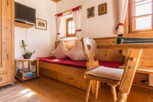 a room with a bed and a chair and a television at Bauernhof im Wiesengrund in Maria Luggau