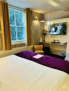 a bedroom with a large bed with a purple blanket at The Forest Lodge in Edwinstowe