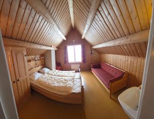 a bedroom with a bed and a red couch in a room at Lauvåsen - Langleiken in Sør-Fron