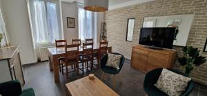 a living room with a dining table and a television at Maison du Gué 2 chambres in Gurgy